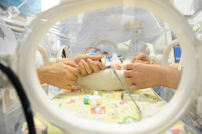 Trabalho de enfermeiros em leito de UTI Neonatal.