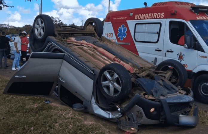 Carro capotado às margens de rodovia no viaduto do Jardim Botânico, com atuação de bombeiros durante atendimento da ocorrência.